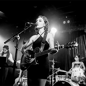 A black and white photo of a woman playing guitar on stage